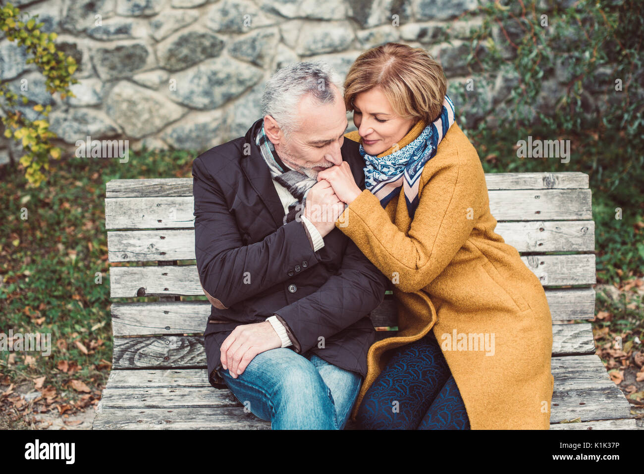 Beautiful mature couple sitting on wooden bench Stock Photo - Alamy