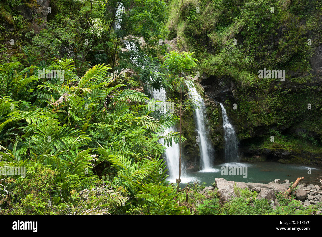 Three waterfalls cascade down mountainous terrain in the Maui rain forest on the Hana trail. Maui is one of the Hawiian Islands. Stock Photo