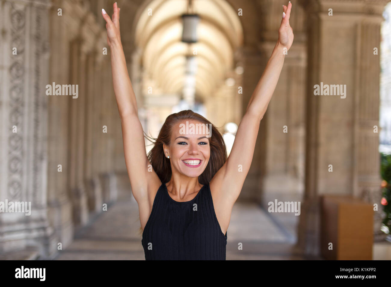 Happy young woman hands up in city, toothy smile, happiness Stock Photo
