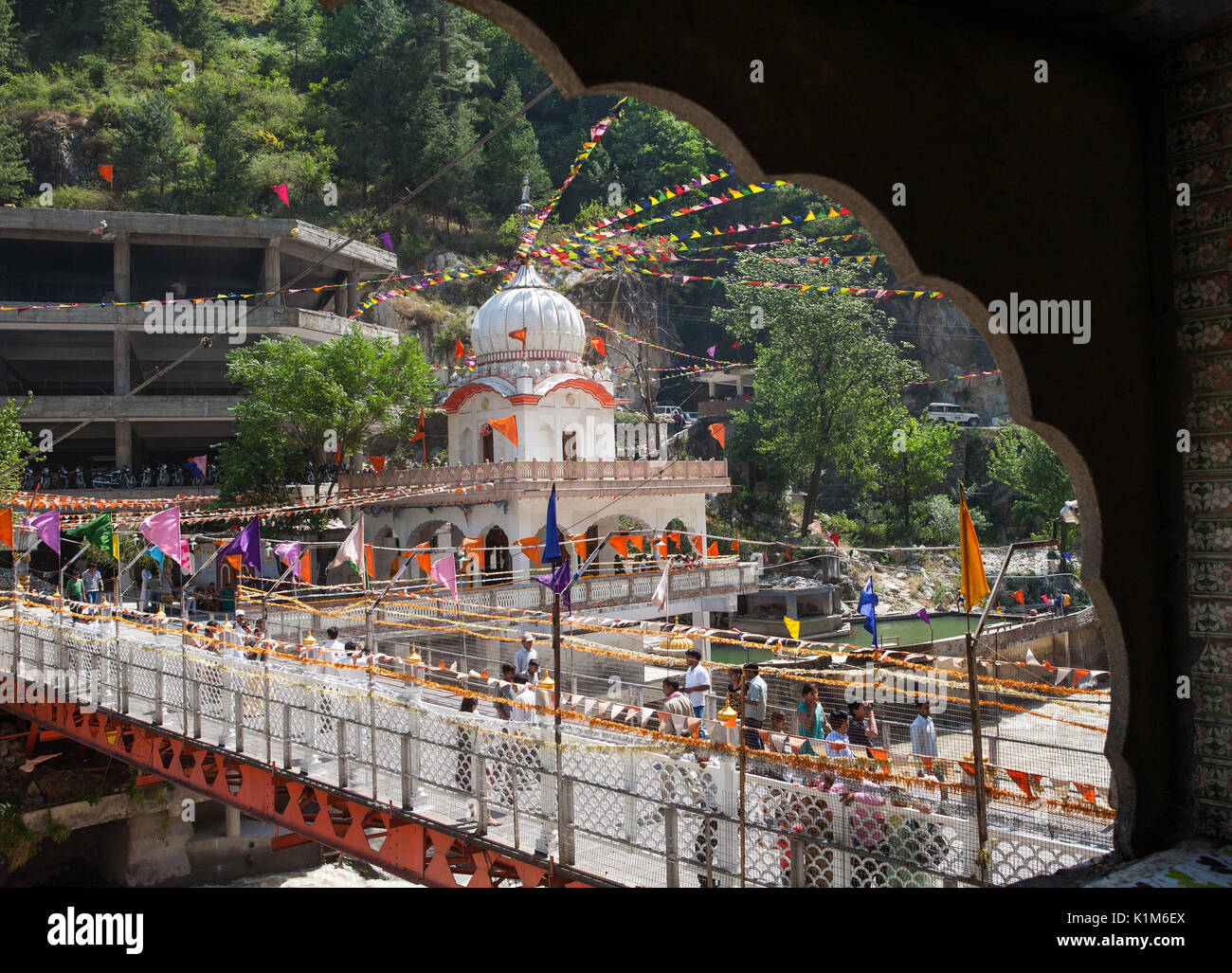 Sacred prayer flags and a bridge across the river Parvati in the Himalayas. Gurdwara Sri Guru Nanak Dev Ji. Manikaran, North India Stock Photo