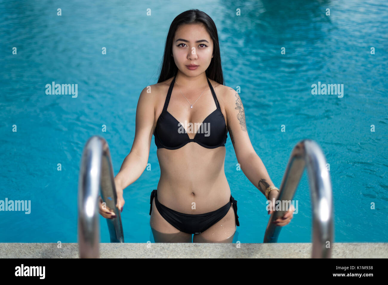 Asian young woman is climbing out of a swimming pool Stock Photo photo