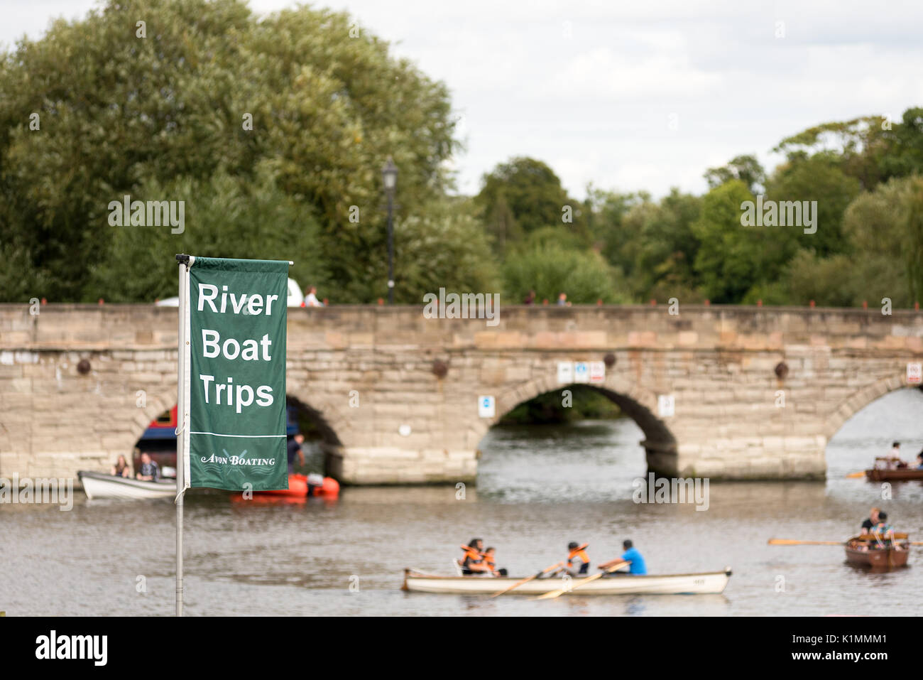The river boat trips flag sign with boaters in the back ground around the Banbury road bridge, Stratford on Avon, Warwickshire. Stock Photo
