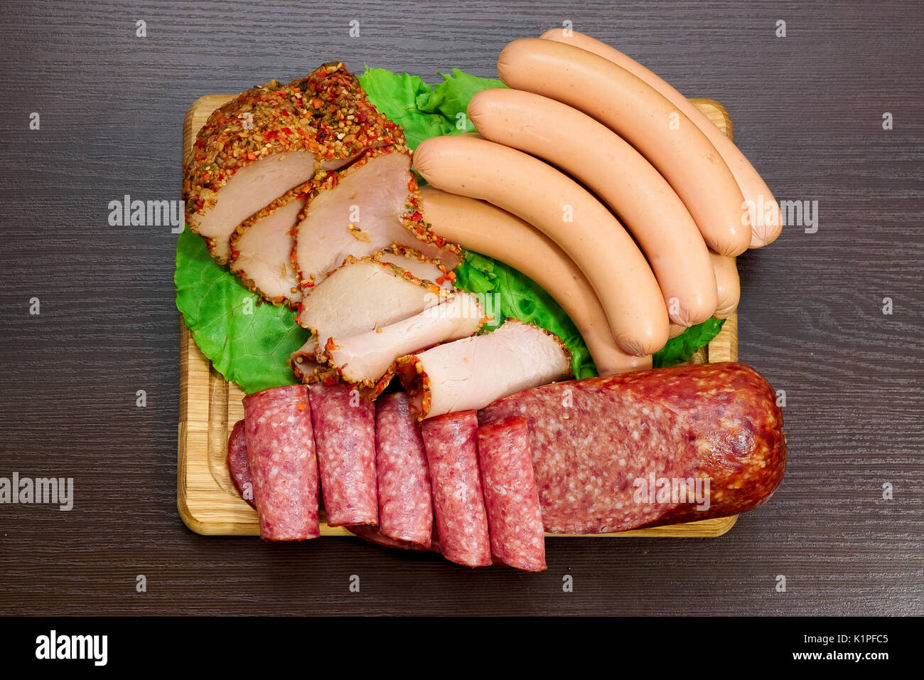 Assorted meat products including ham and sausages on cutting board. Top view Stock Photo