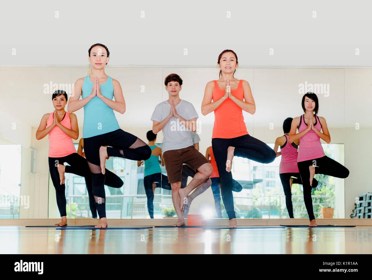 Yoga class in studio room,Group of people doing tree pose and namaste ...
