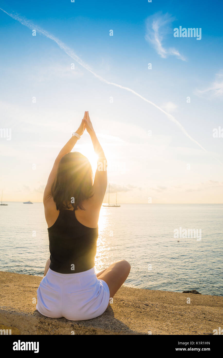 Young brunette woman (25-30) stretching while overlooking the sea in the Summer Stock Photo