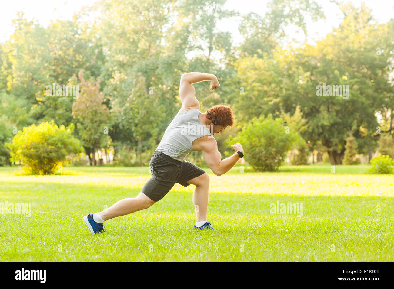 Workout in summer morning. Muscules redhead athlete posing, at camera. Outdoor Stock Photo