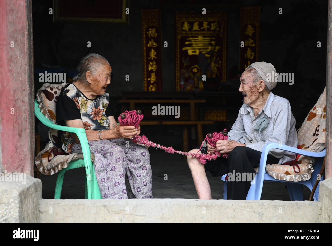 Fengjie, China's Chongqing Municipality. 23rd Aug, 2017. Xiang Yongshan (R) and his wife Wu Xi'an sit at the doorway and hold their love token, the bronze bell, in Zaojiao village of Fengping township, Fengjie County, southwest China's Chongqing Municipality, Aug. 23, 2017. 100-year-old Xiang and 101-year-old Wu has been married for 81 years. Credit: Wang Quanchao/Xinhua/Alamy Live News Stock Photo
