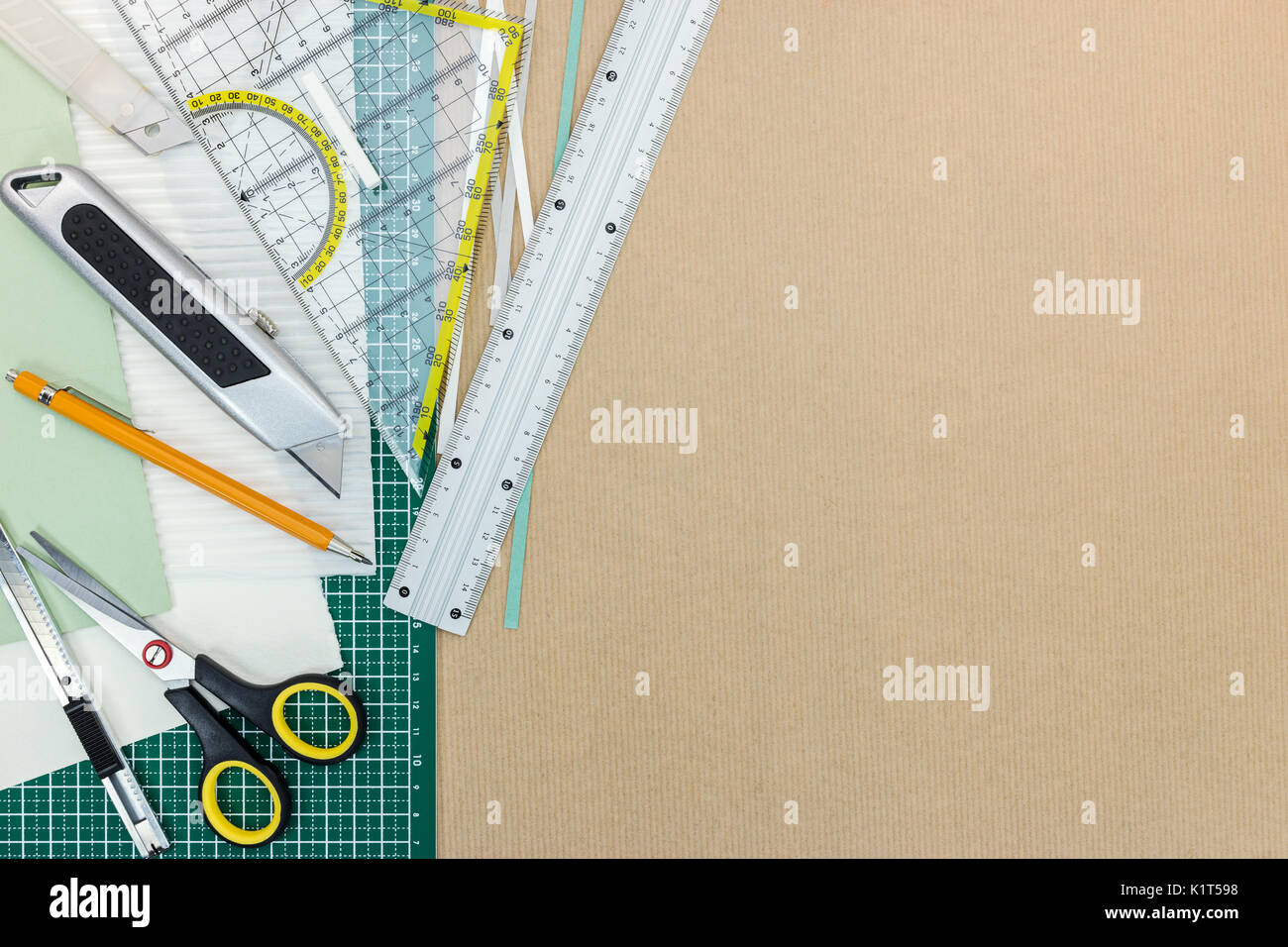 working desk with green cutting mat, cutter, ruler, scissors an pencil