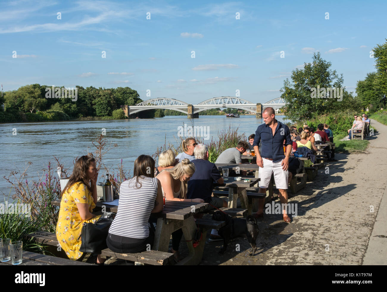 People enjoying a quiet drink, next to the River Thames, outside the
