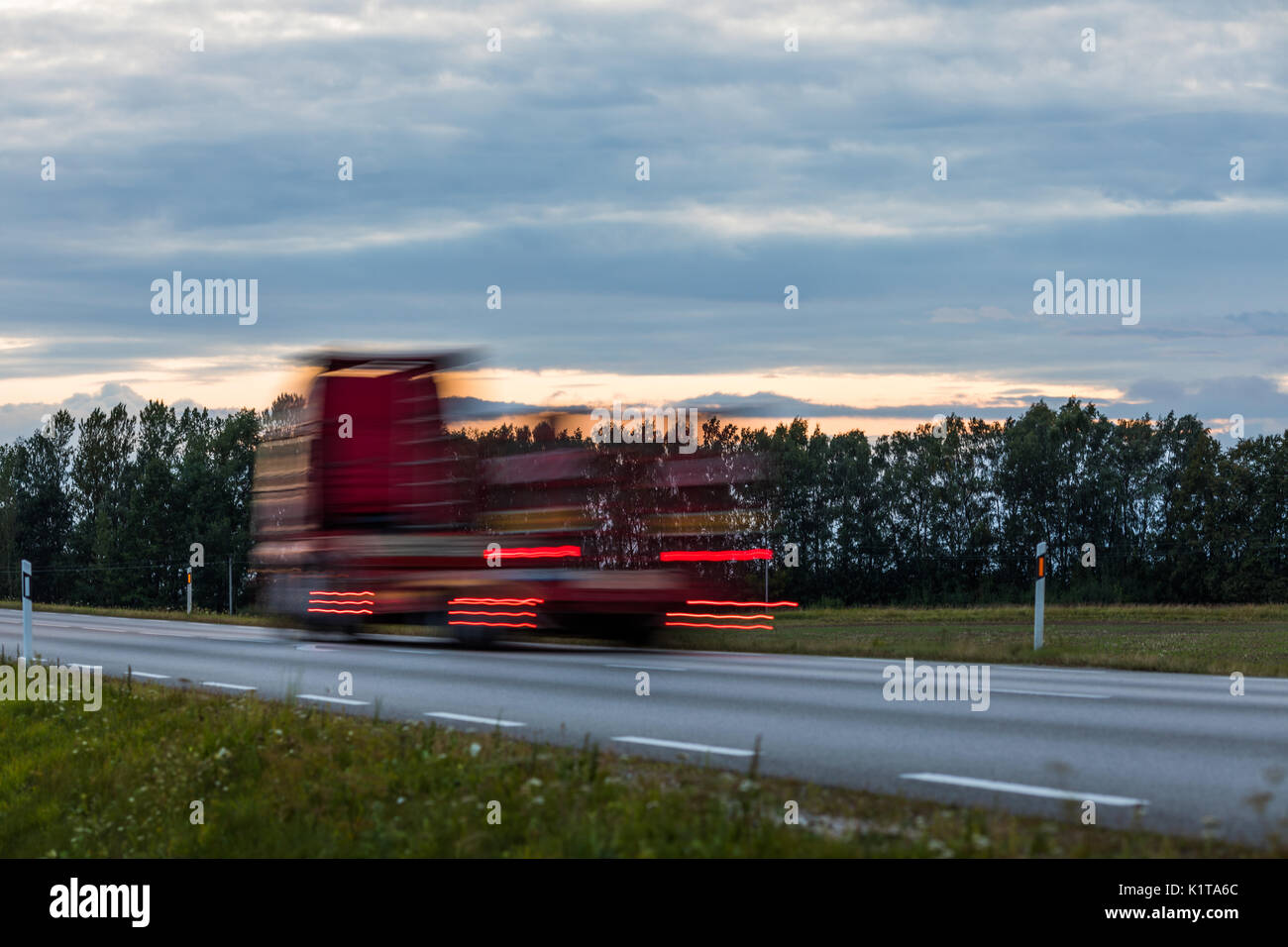 Speeding motion blur oncoming trucks with glowing lights on the highway after sunset. Abstract blur image background with copy space. Stock Photo