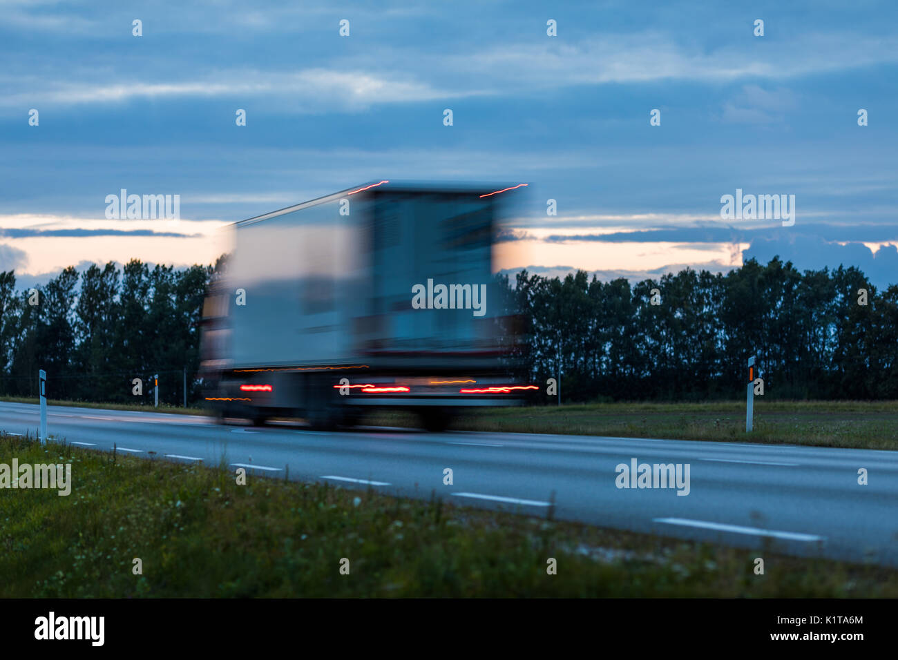 Speeding motion blur oncoming trucks with glowing lights on the highway after sunset. Abstract blur image background with copy space. Stock Photo