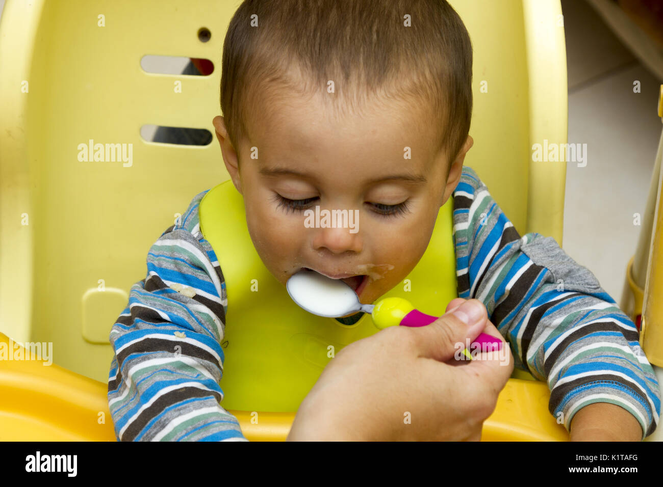 lovely 18 months baby eats yogurt indoor face eating Stock Photo Alamy