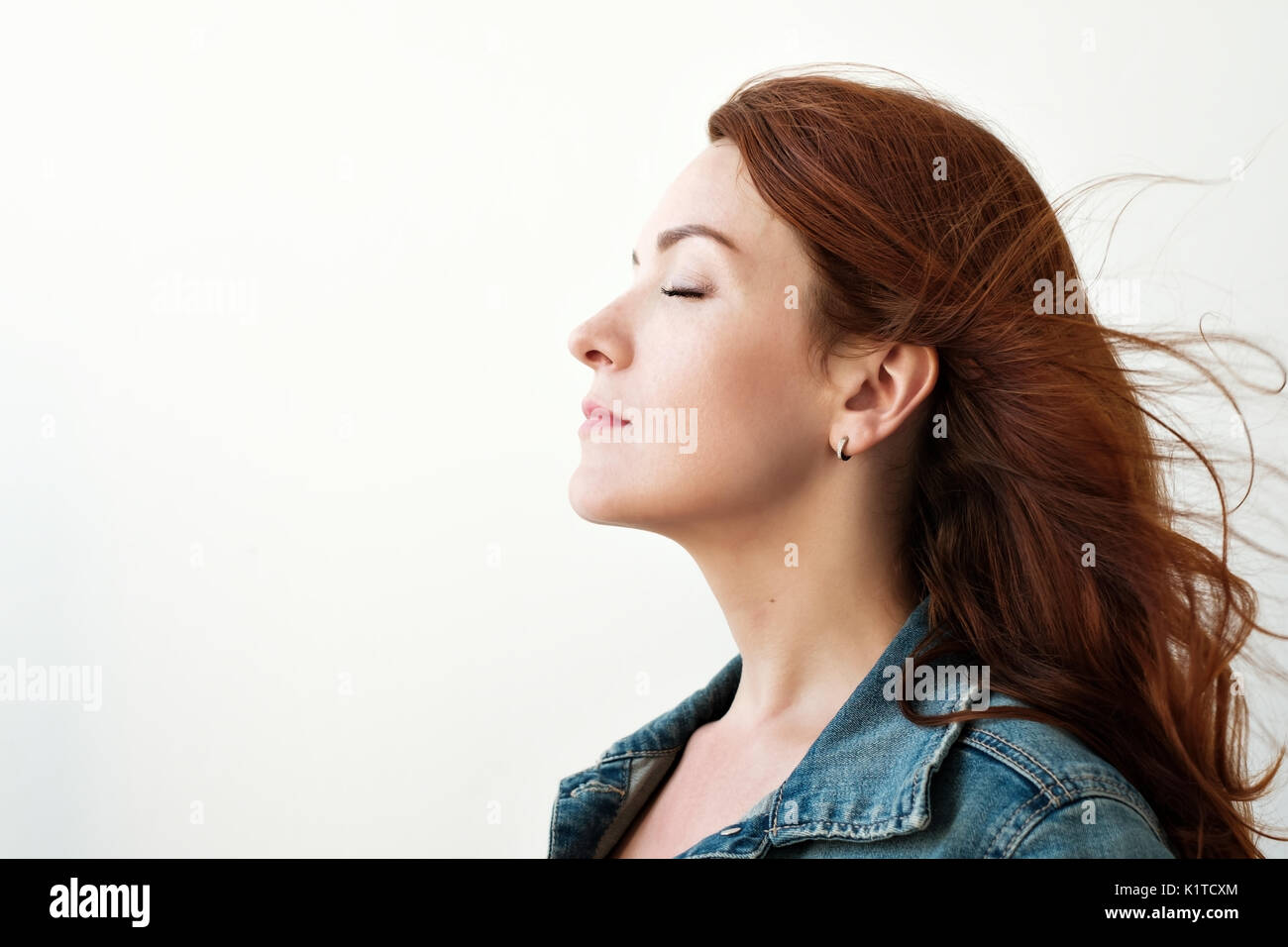 Portrait of a beautiful red-haired woman. She looks away in an inspired way, dreaming about something. Stock Photo