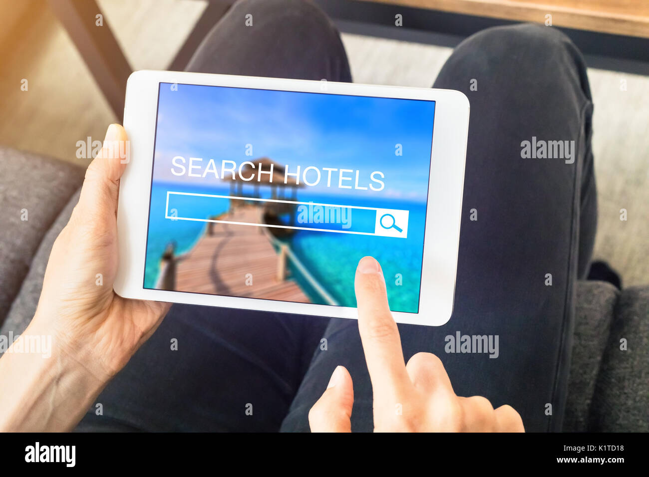 Person searching hotel room to book online with a tablet computer and using a search engine website, planning vacations Stock Photo