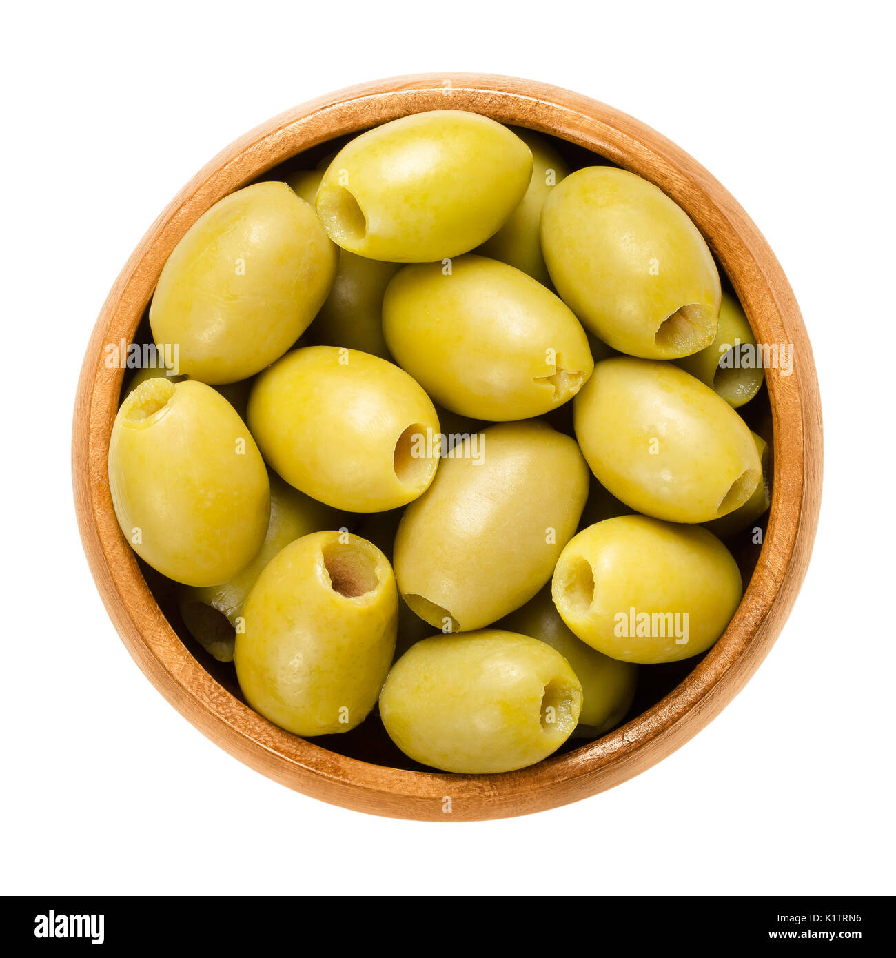 Pitted and marinated green olives in wooden bowl. Fruits of the European olive, Olea europaea. Unripe table olives with yellow to green color. Stock Photo