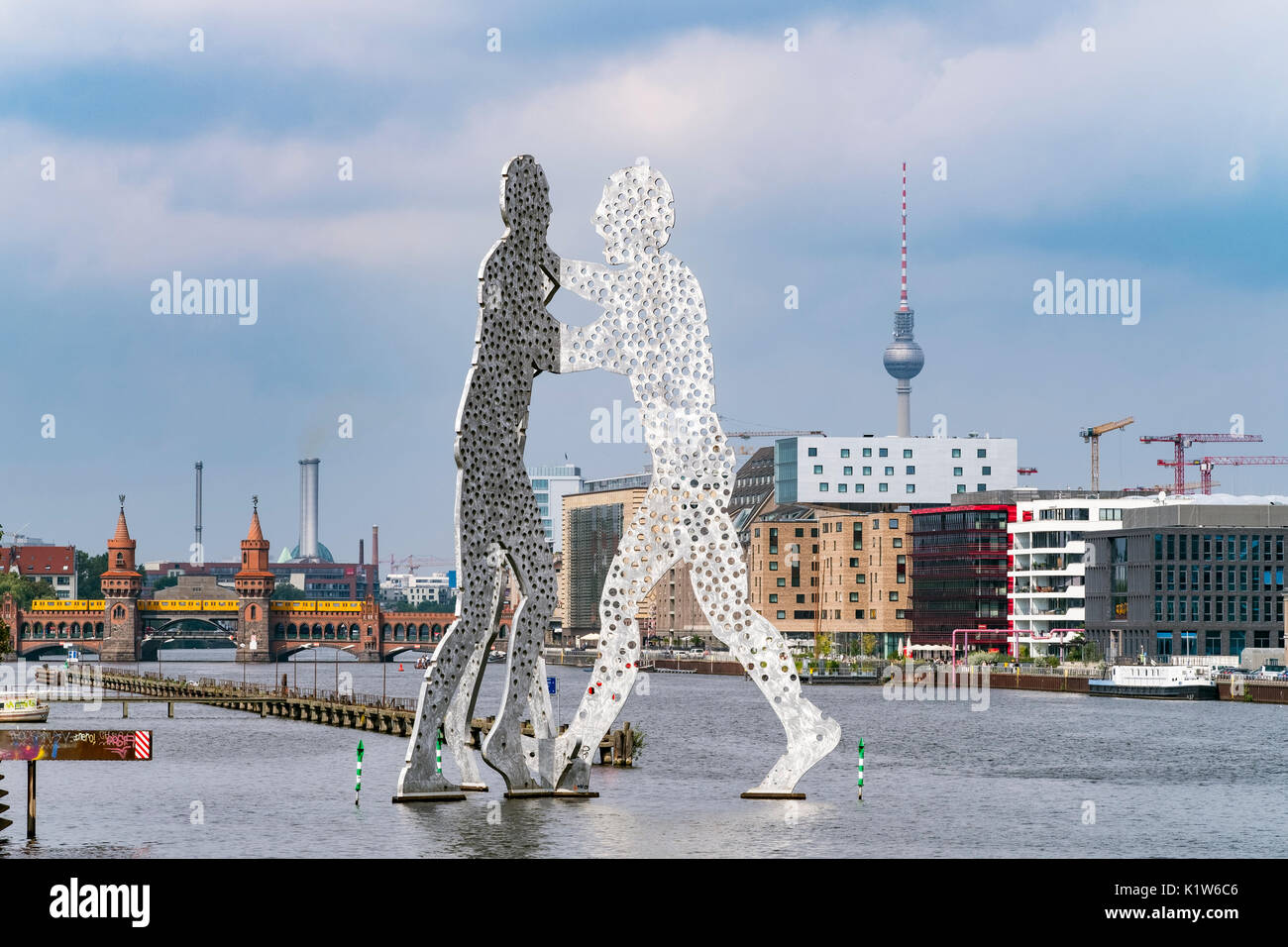 Skyline of Berlin across River Spree with large sculpture Molecule Man in Berlin Germany Stock Photo