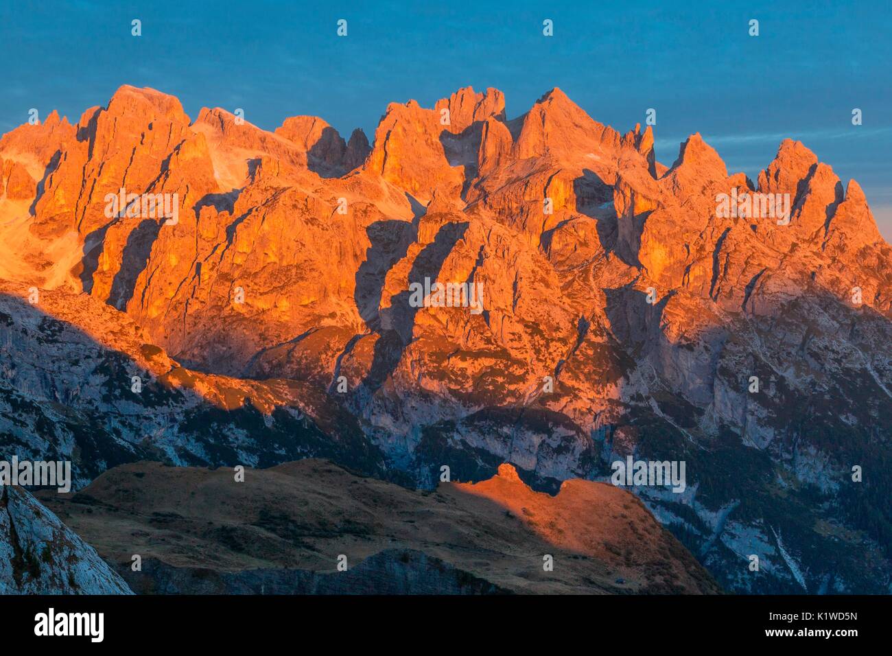Enrosadira (alpenglow) at sunrise on the Pale di San Martino, Dolomites in an autumn morning. The phenomenon of alpenglow is repeated day after day on Stock Photo