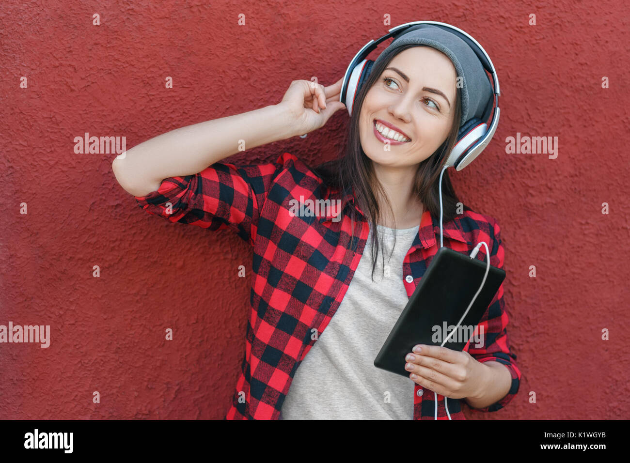 young woman with tablet computer listening music in headphones. Girl using digital tablet. Technology, music, lifestyle, and millenial people concept Stock Photo