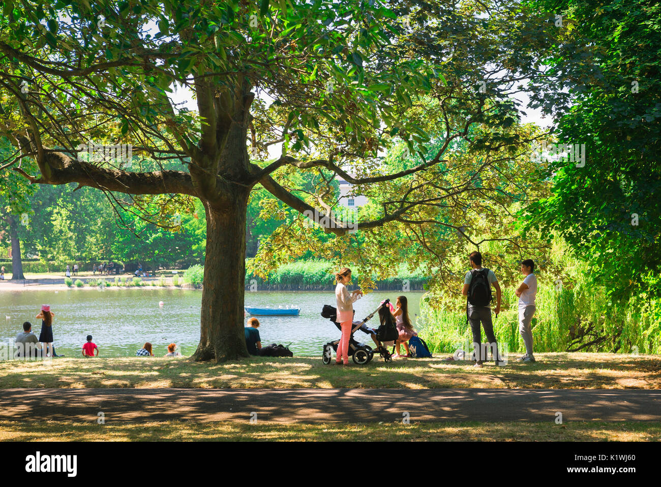 London park summer, on a summer afternoon tourists picnic beside the boating lake in Regent's Park, London, UK. Stock Photo