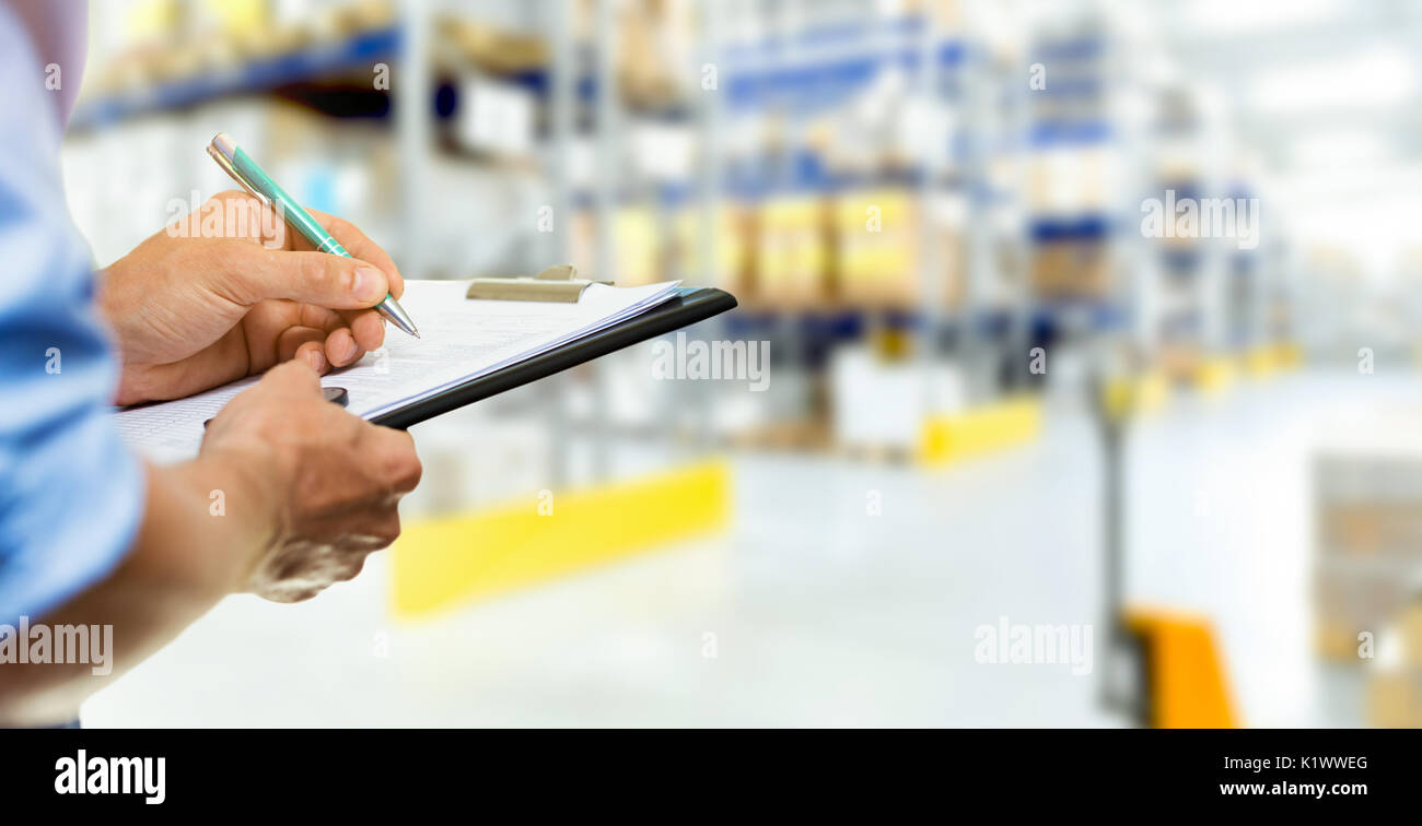 logistics service man writing documents on clipboard in warehouse Stock Photo