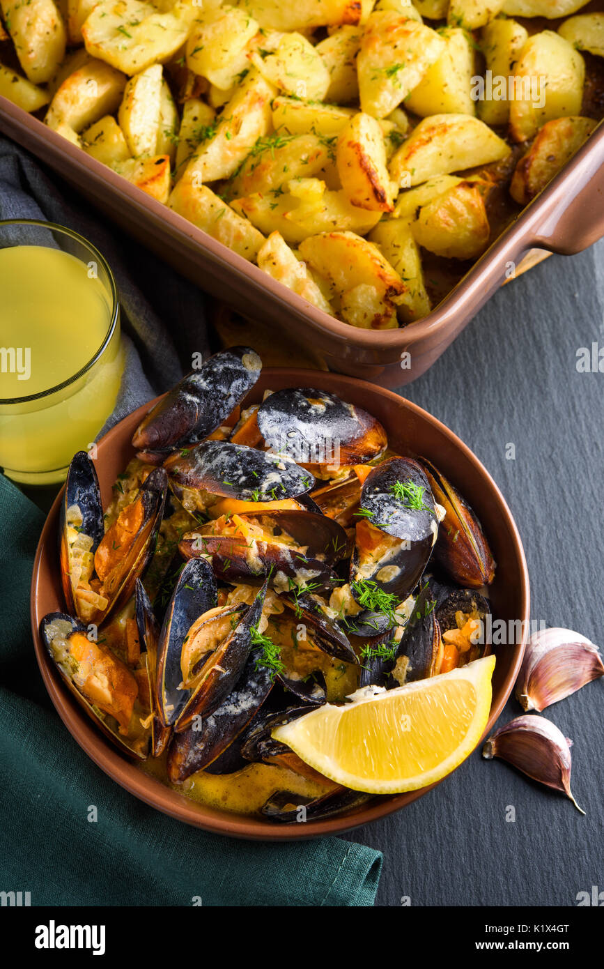 Shellfish mussels in bowl served with baked potato with celery, garlic