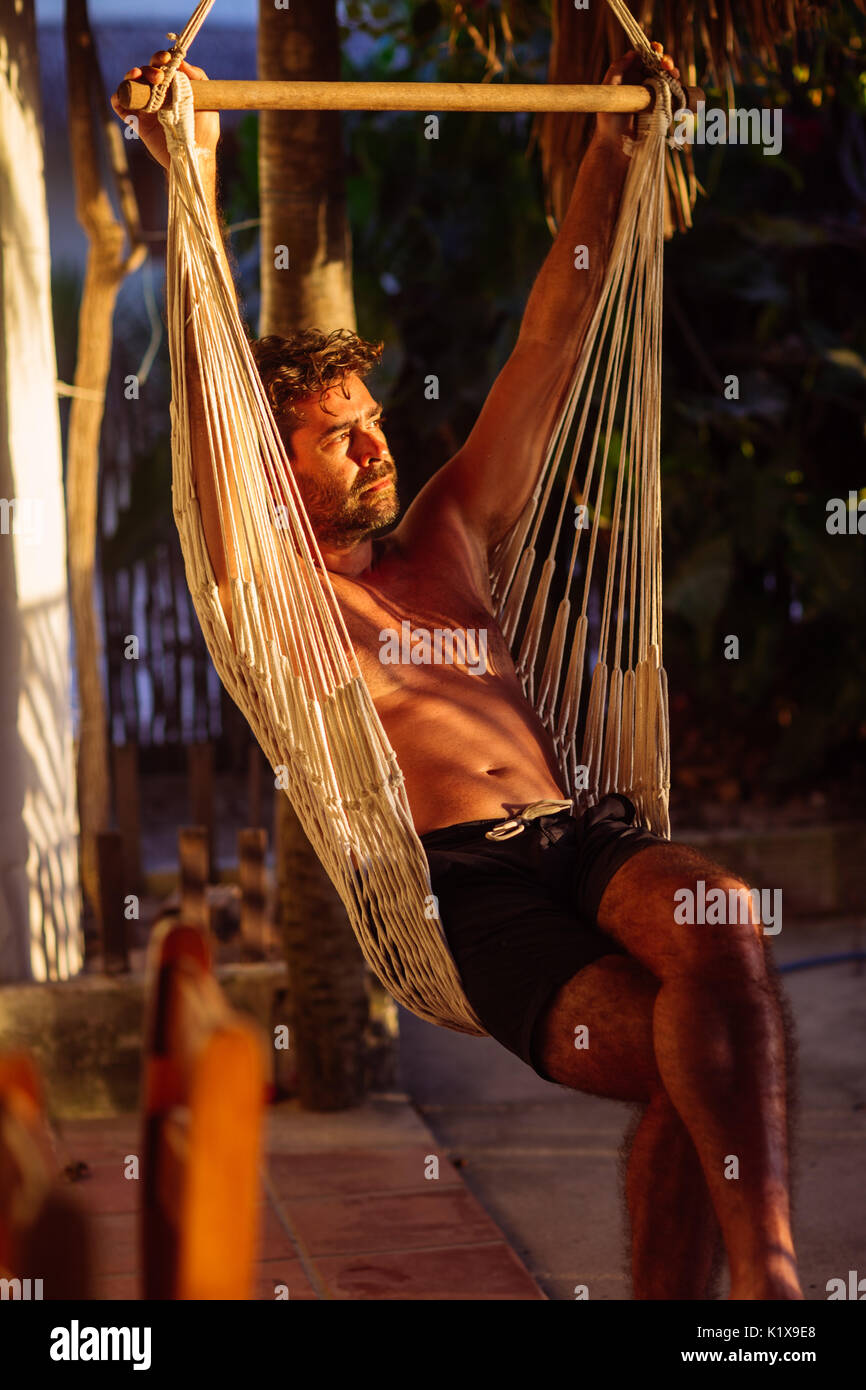 Middle age man sitting on a hammock in the porch of a house, watching the  sunset in Jericoacoara, Ceará, Brasil Stock Photo - Alamy