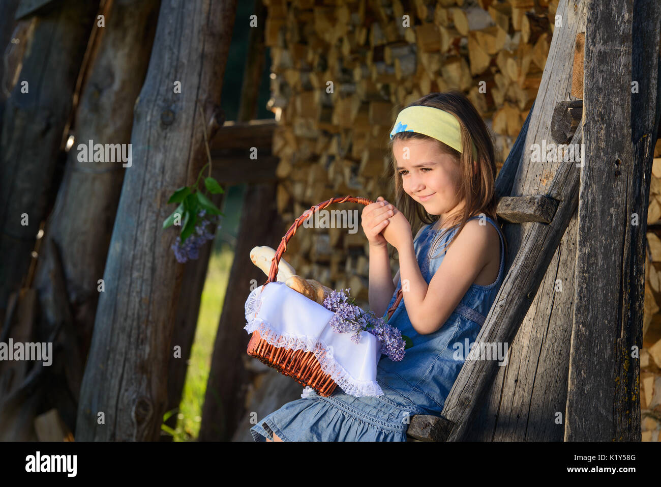 Cute smiling little girl holding a basket of flowers. Portrait in profile. Stock Photo