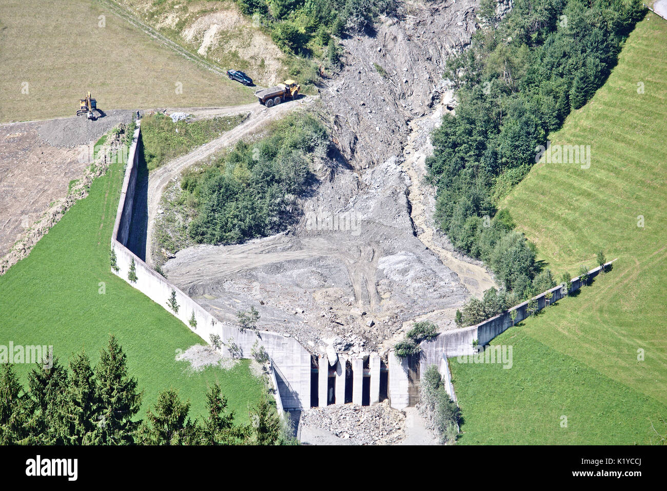 Aerial view of mountain stream in the Austrian Alps blocked after a massive mudflow with excavator and truck working to clean up the site Stock Photo
