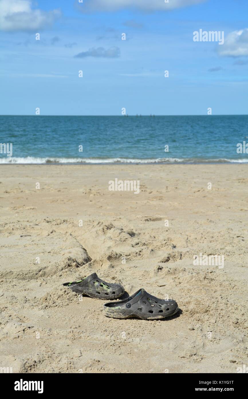 A few shoes on the sandy beach with sea in the background Stock Photo