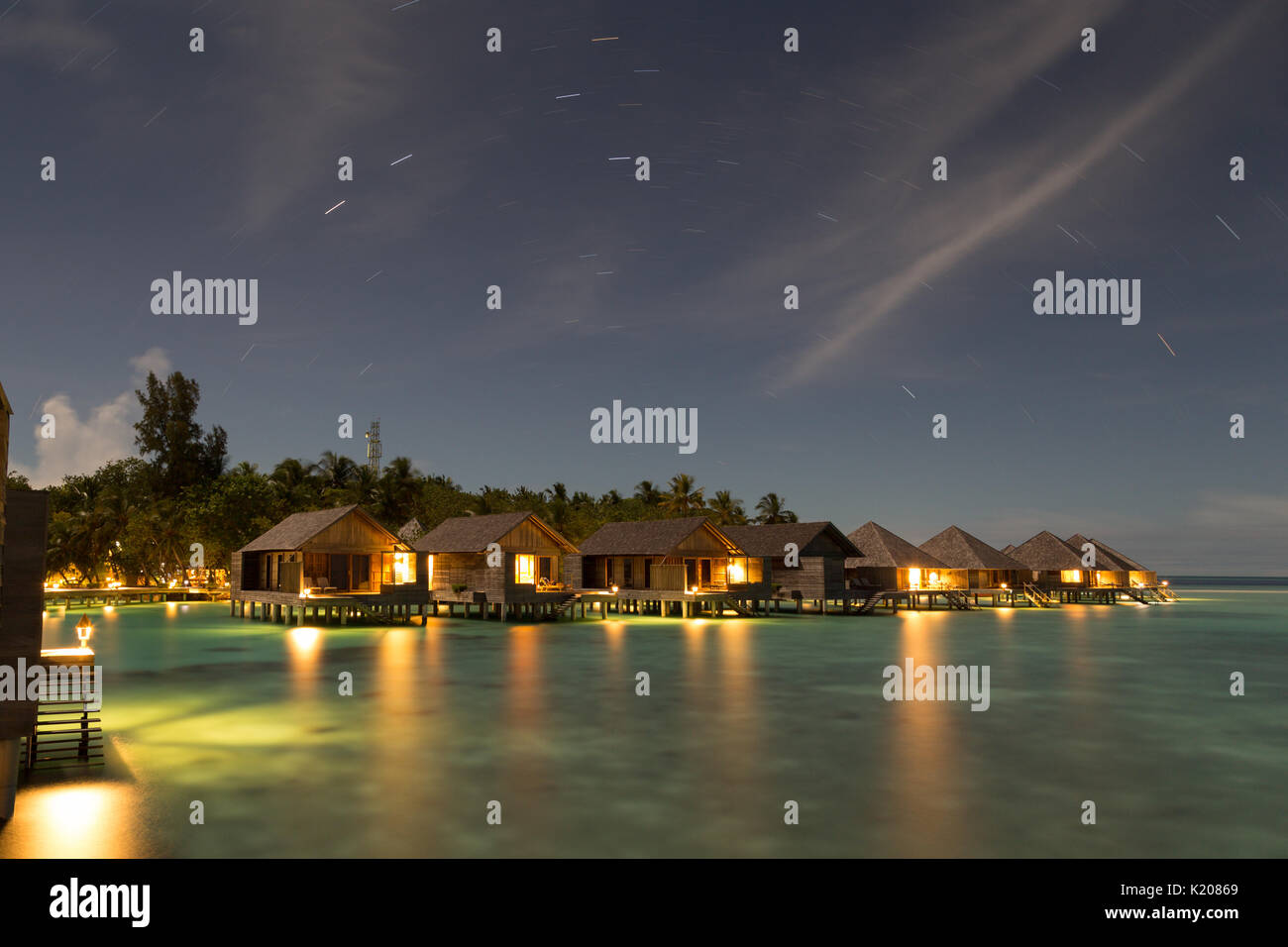 Wooden huts on stilts in lagoon at night, Gangehi Island, Ari Atoll, Indian Ocean, Maldives Stock Photo