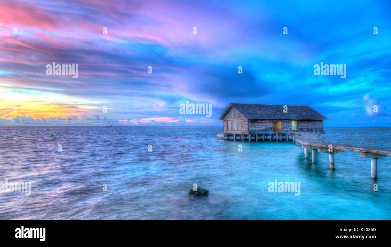 Wooden hut on stilts in lagoon, cloudy sky, twilight, Gangehi Island, Ari Atoll, Indian Ocean, Maldives Stock Photo