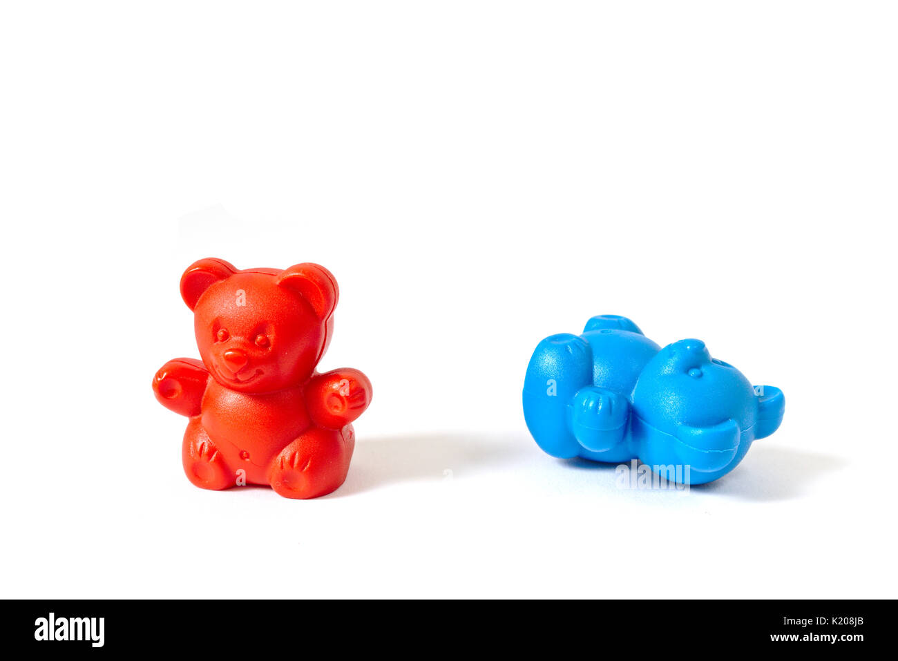Plastic toy bears in the colors of the Democratic and Republican Party with the red bear standing and the blue bear knocked over Stock Photo