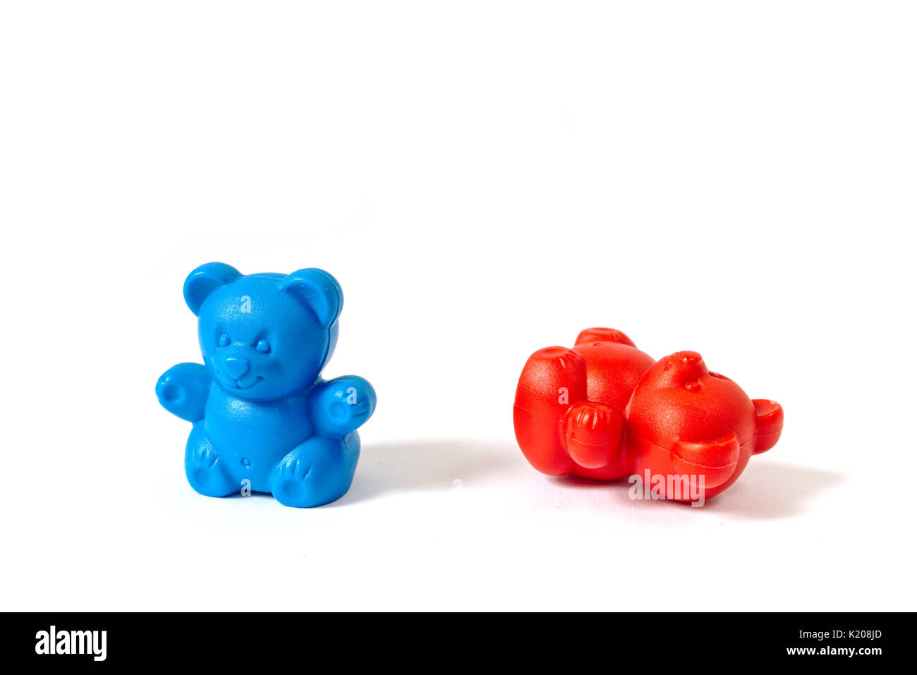 Plastic toy bears in the colors of the Democratic and Republican Party with the blue bear standing and the red bear knocked over Stock Photo