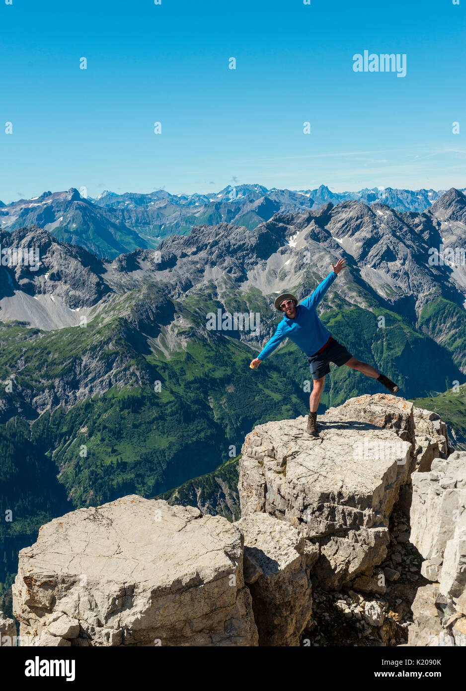 Hiker standing on one leg, mountains and Alps, summit of Hochvogel, Allgäu, Allgäu High Alps, Bavaria, Germany Stock Photo