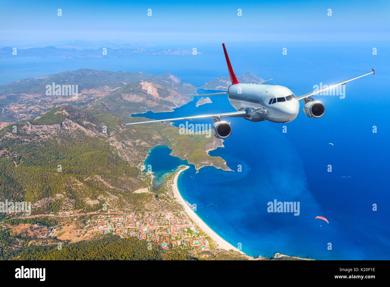 Airplane is flying over amazing islands and mediterranean sea at bright day. Landscape with white passenger airplane, mountains and blue water. Passen Stock Photo