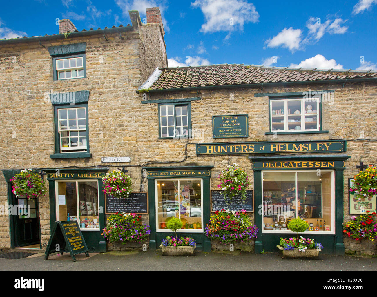 Hunters of Helmsley, delicatessen in historic building with stunning display of hanging baskets & tubs of flowers in village in Yorkshire, England Stock Photo