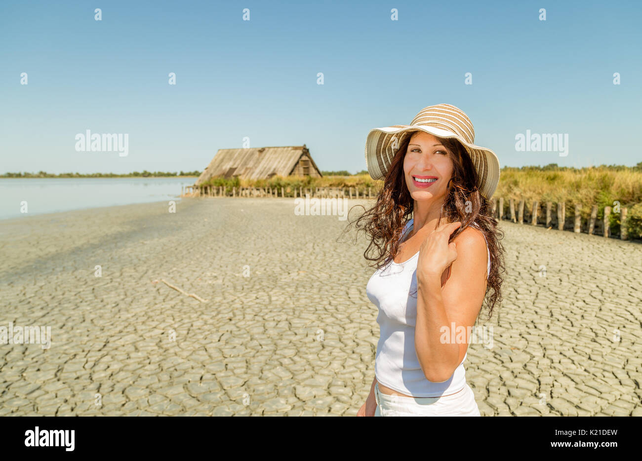 Attractive mature woman in wide hat playing with hair on a cracked ...