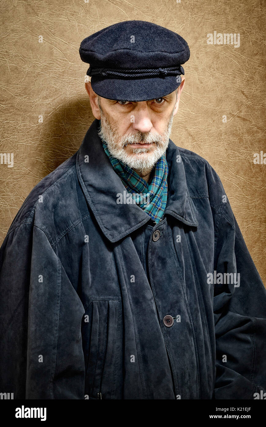 Portrait of a mature man with a white beard and a cap on the head. He could be a sailor, a worker, a docker, or even a gangster or a thug. He has a pe Stock Photo