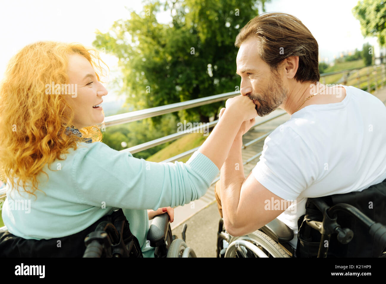 Senior disabled man kissing a hand of his loving wife Stock Photo