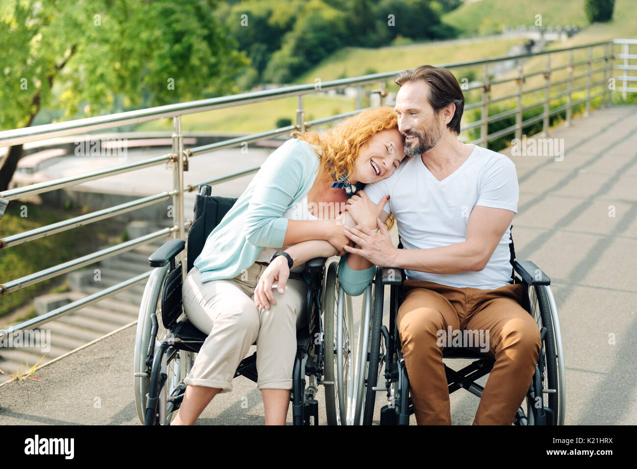 Cheerful senior woman embracing her loving wheelchaired husband Stock Photo