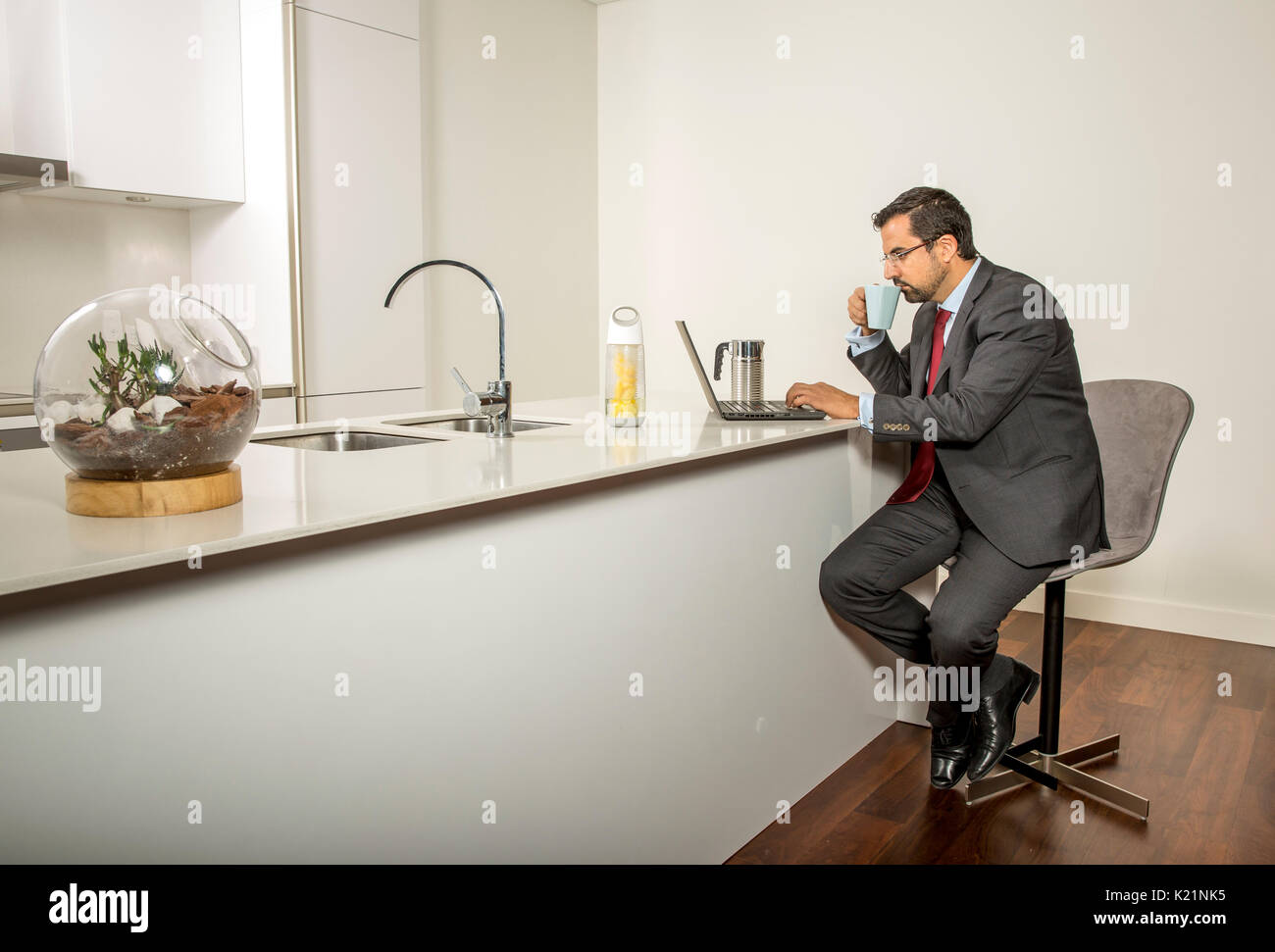 arab man in formalware working in  his computer in a kitchen of his urban apartment Stock Photo