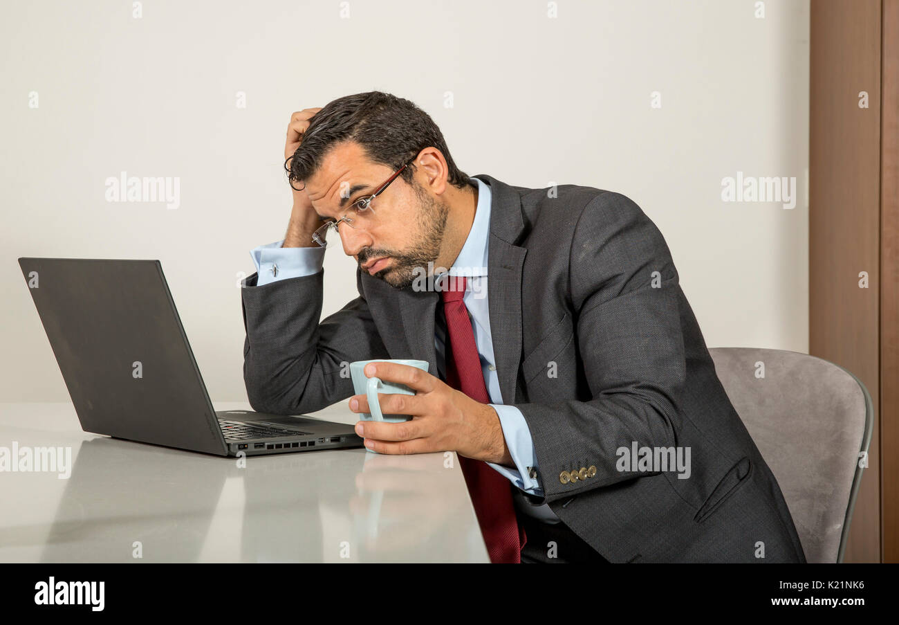 arab man in formalware working in  his computer in a kitchen of his urban apartment Stock Photo
