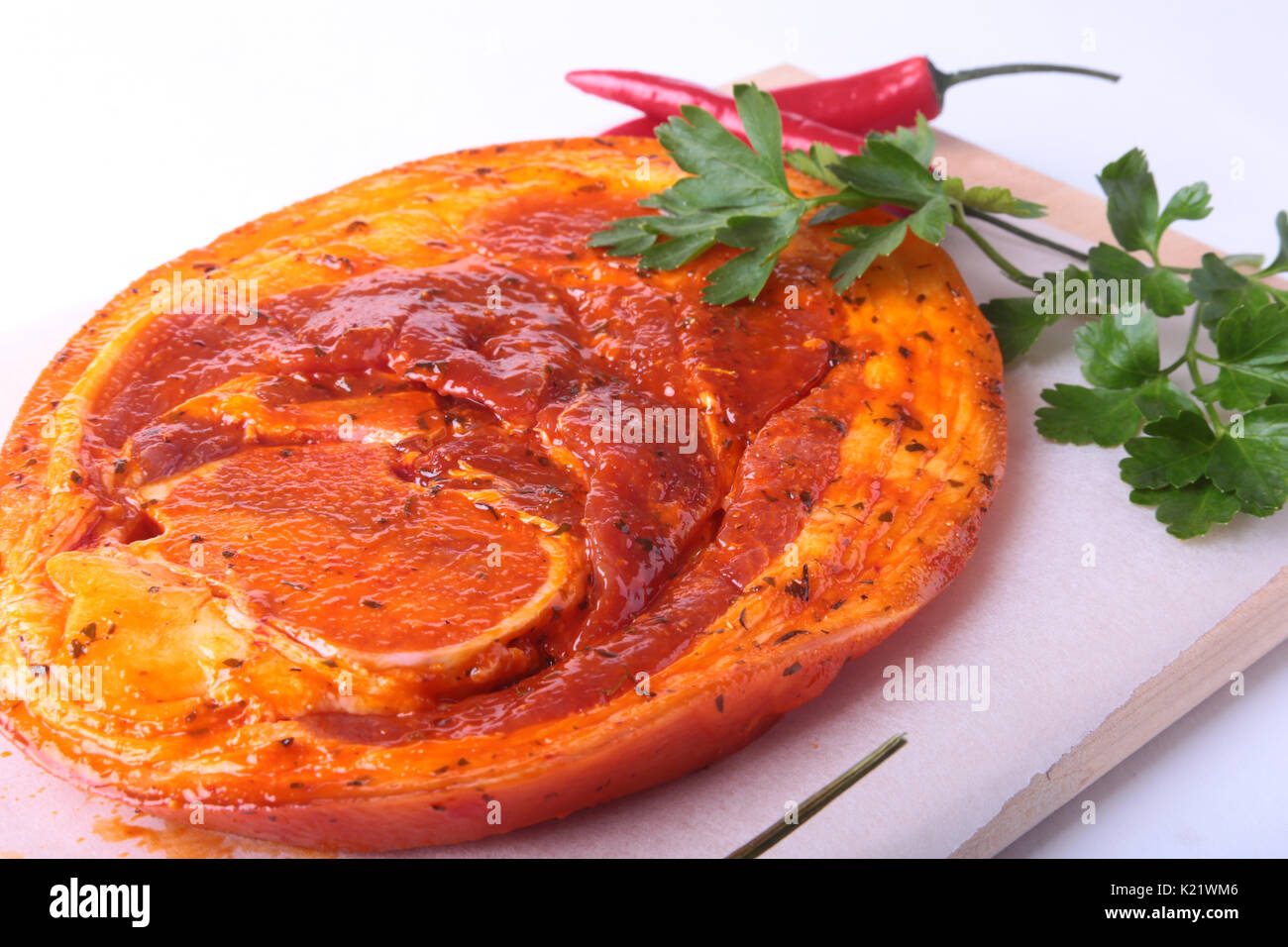 Raw Pork ham with spices, parsley leaves and chilli ready for BBQ grilling isolated on white background. Stock Photo