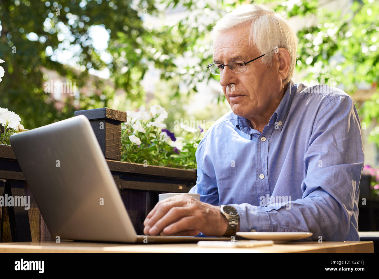 Modern Senior Man Using Laptop in Cafe Stock Photo