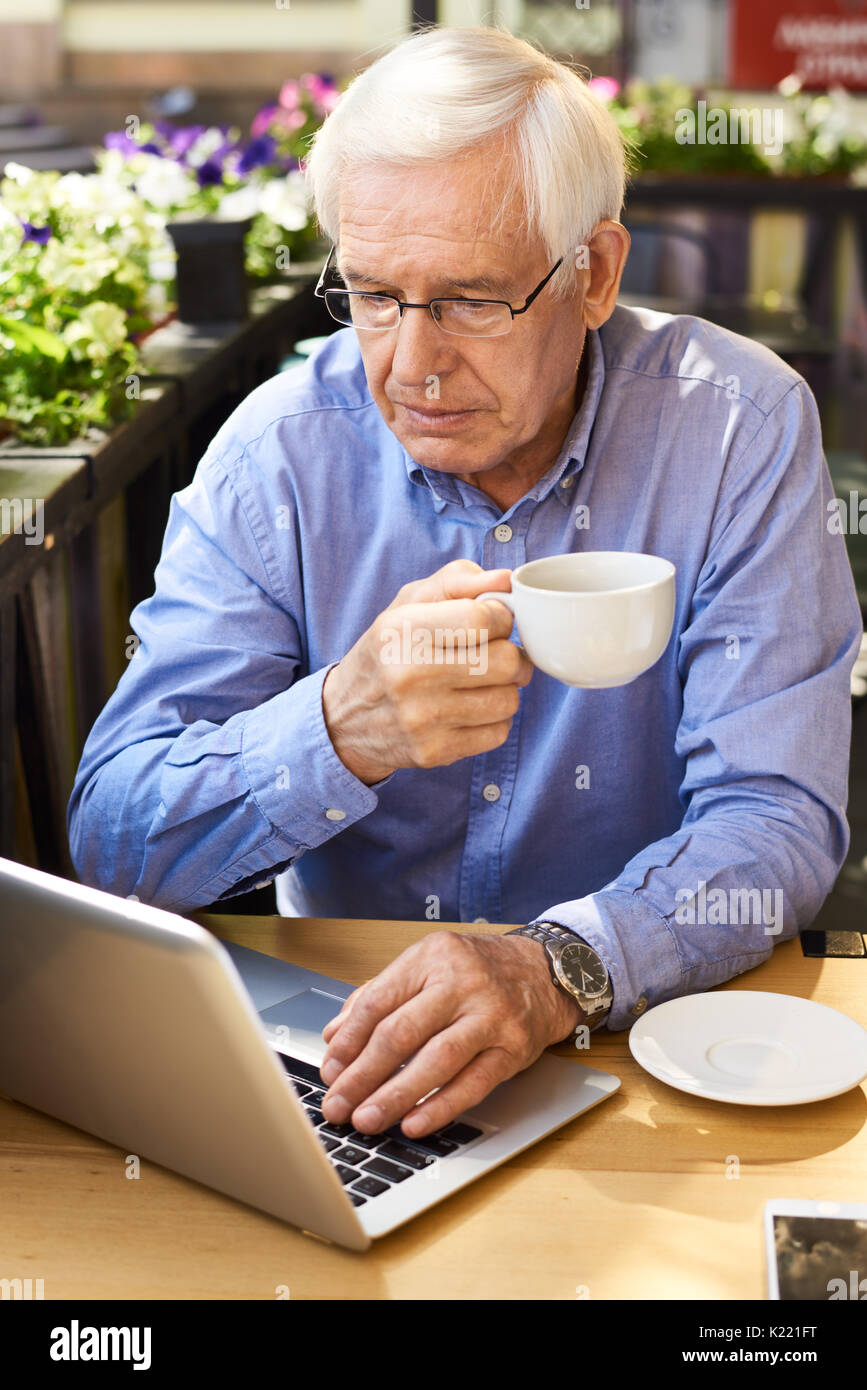 Modern Senior Man Using Laptop  at Coffee Break Stock Photo