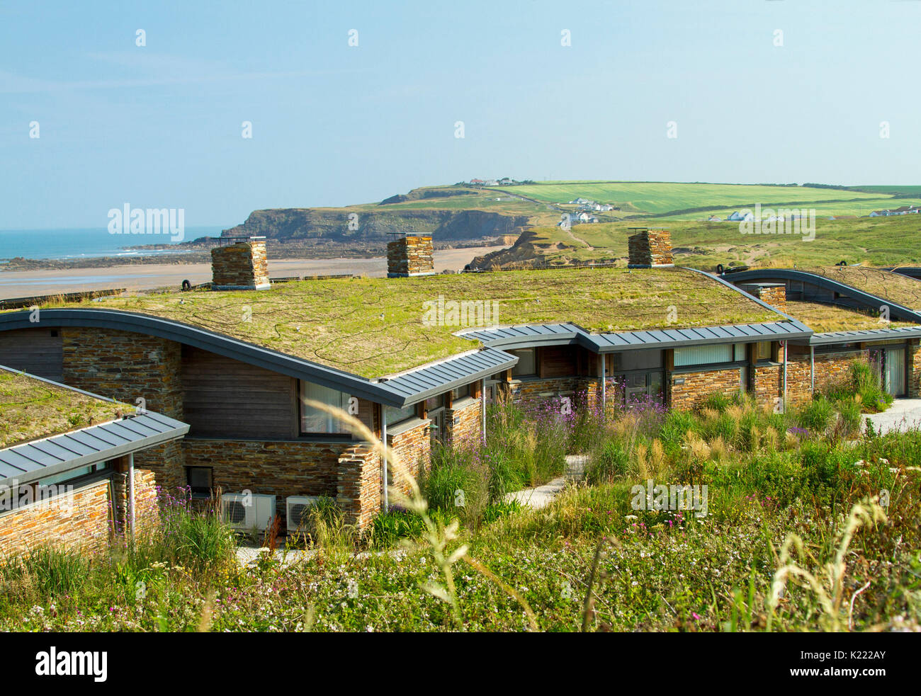 Modern house / bungalow with insulating sod roof / green living roof and black piping for solar water heating at Widemouth Bay, Cornwall, England Stock Photo
