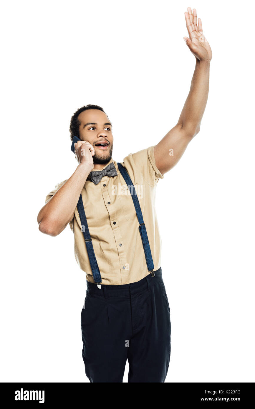 african american man waving and using smartphone, wearing in suspenders and bow tie isolated on white Stock Photo