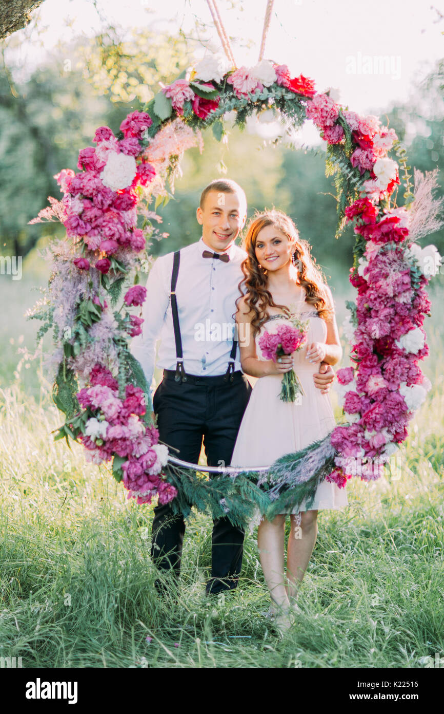 The bridesmaid and the best man are posing through the wedding flower