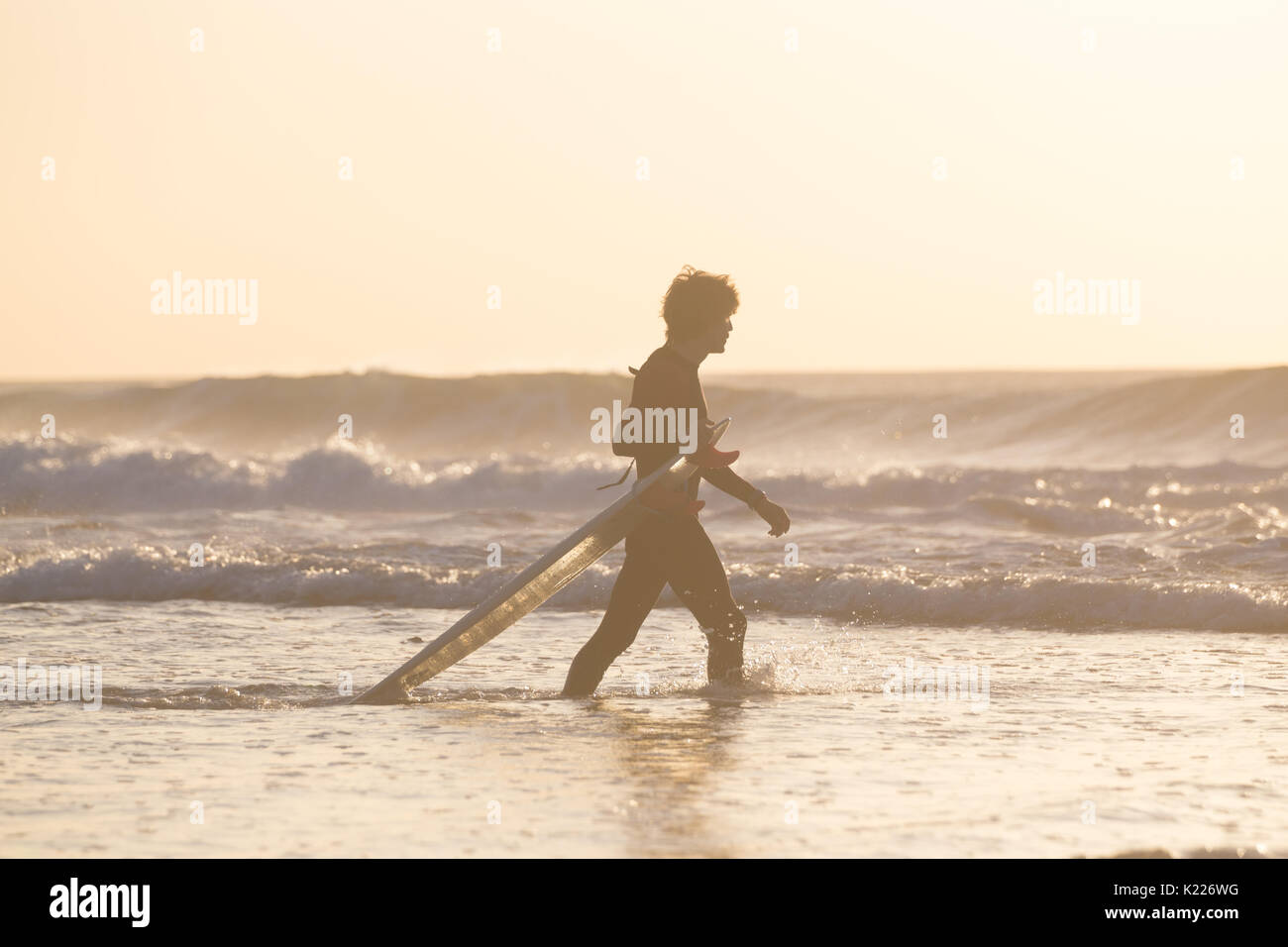 Silhouette of surfer on beach with surfboard. Stock Photo