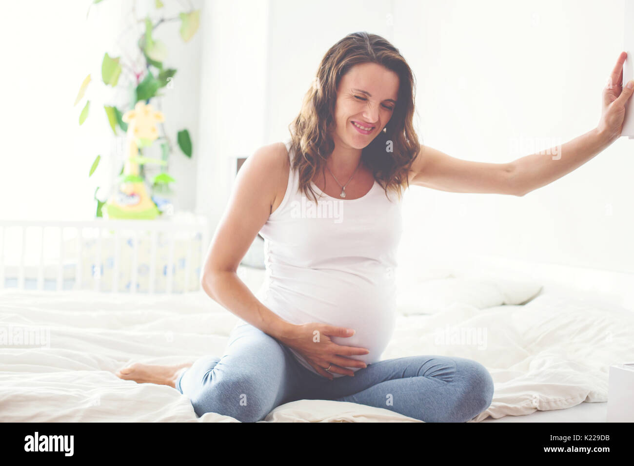 Young beautiful pregnant woman, in pain with labor contraction, sitting